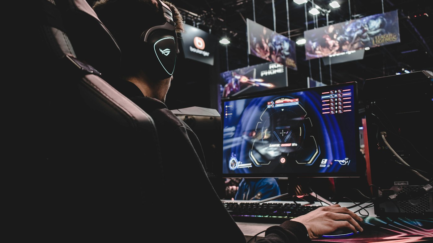 Gaming-Arbeitsplatz mit Monitor und Tastatur im Neonlicht als Sinnbild für niedrige Latenz beim Online-Spielen
