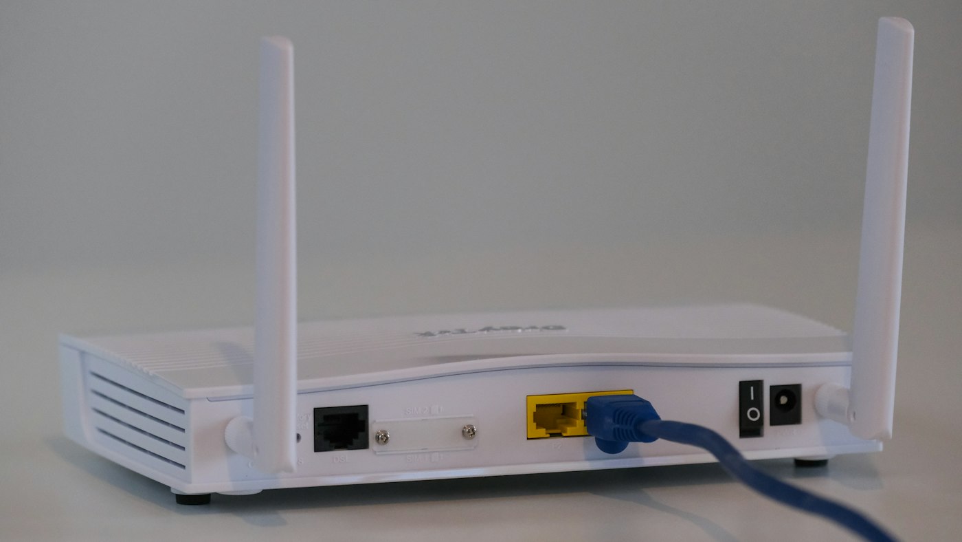 WLAN-Router auf einem Regal mit angeschlossenen Kabeln als Symbol für die Wahl zwischen eigenem Router und Anbieter-Hardware