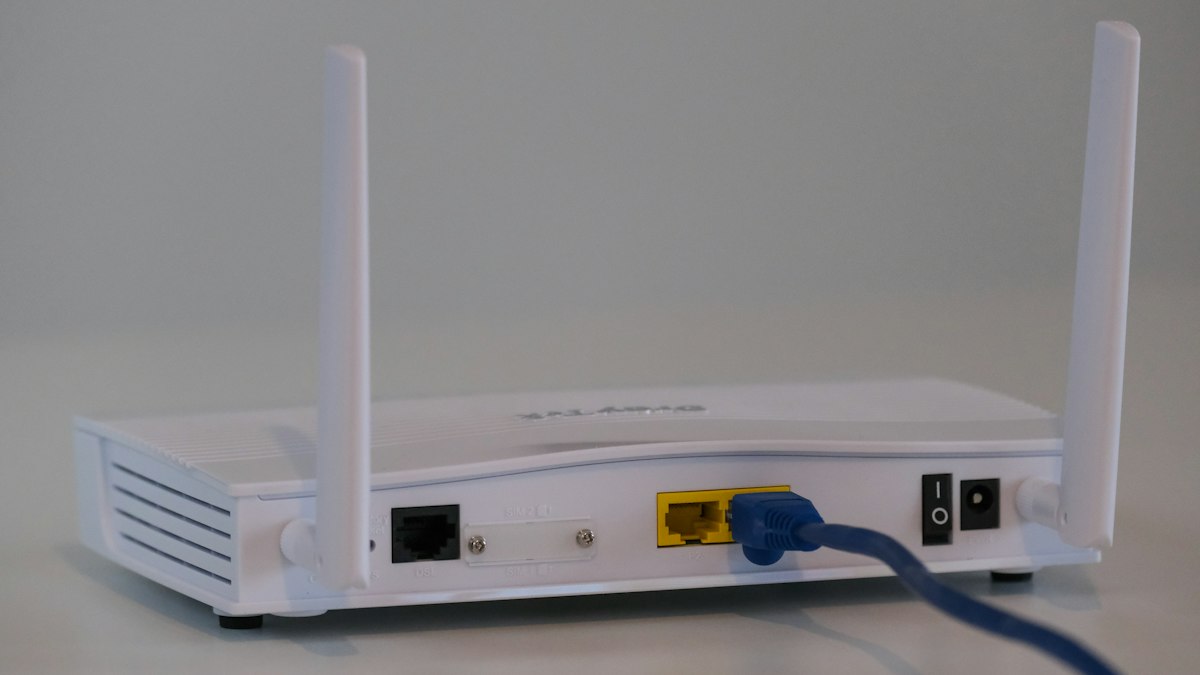 Nahaufnahme eines WLAN-Routers mit Antennen und Netzwerkkabeln